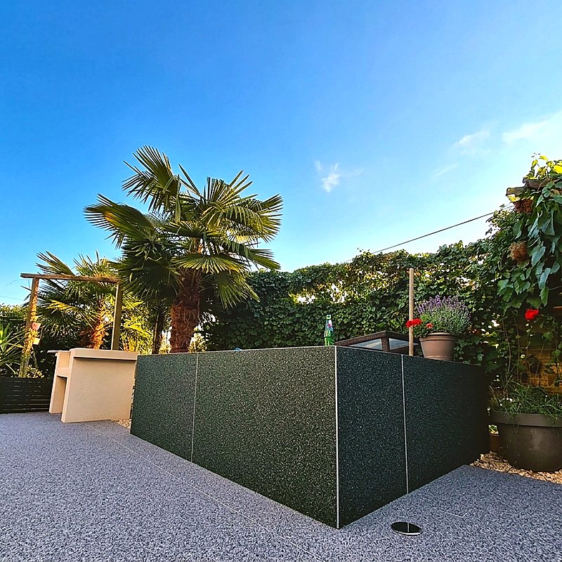 Terrasse en moquette de pierre grise et muret vert