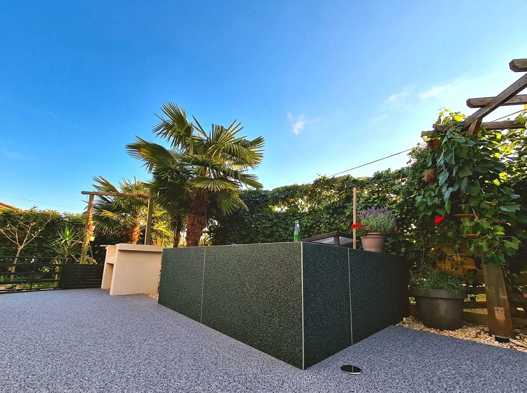 Terrasse en moquette de pierre grise et muret en granulat vert à Hagetmau